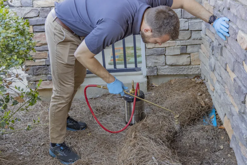 Trent Mobley of Berner Pest Solutions treating the foundation of a Lexington area home during a scheduled service visit