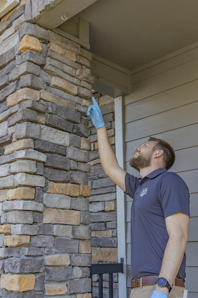 Berner Pest Solutions technician inspecting a porch column for wasp and stinging insect activity in Lexington KY