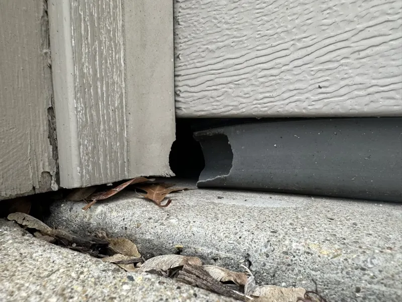 A worn corner gap at an overhead door, the kind of small opening rodents use to enter storage buildings